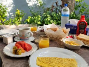 a table topped with plates of breakfast food and orange juice at The Sandscape Fuvahmulah in Fuvahmulah