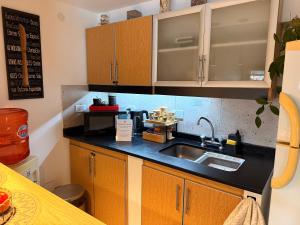 a kitchen with wooden cabinets and a sink at Espacio Nidra - Tu descanso a pasos del Aeropuerto in Ezeiza