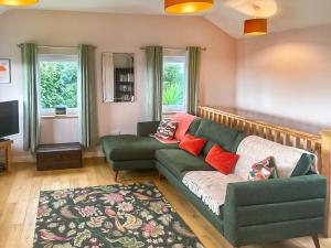 a living room with a green couch and a tv at Hollinhaven in Blackwaterfoot