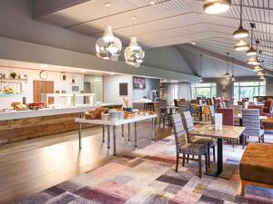 a restaurant with tables and chairs and a counter at Novotel Manchester West in Worsley