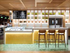un restaurant avec deux tabourets de bar et un comptoir dans l'établissement Novotel York Centre, à York