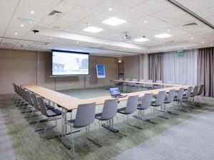 une salle de conférence avec une longue table, des chaises et un écran dans l'établissement Novotel York Centre, à York 179 autres photos