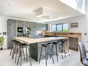 a kitchen with a large island with bar stools at The Black Barn in Marldon