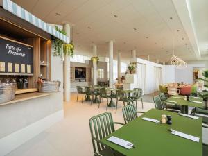 a restaurant with green tables and chairs at Novotel Brugge Centrum in Bruges