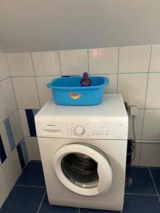a washing machine with a blue bucket on top of it at Yellow Attic in Senhora do Rosário