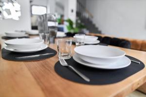a wooden table with white plates and glasses on it at MM Suites Town House Terrasse in Reims