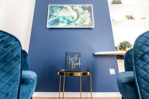 a blue room with two chairs and a table with a sign on it at MM Suites Marlot in Reims +10 photos