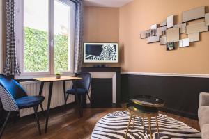 a living room with a table and chairs and a tv at MM Suites Reims Centre Terasse in Reims