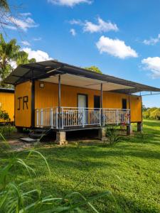 a small yellow house with a porch in a field at Le Ghirol - Tiny Houses & Nature in Quesnel