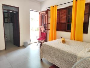 a bedroom with a bed and a window with yellow curtains at Barros Homestay in Tarrafal