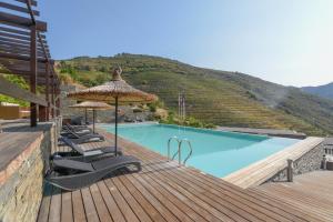 a pool with chairs and umbrellas on a wooden deck at Hotel Rural Quinta Do Pego in Tabuaço