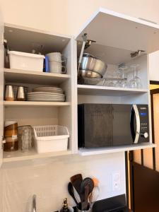 a kitchen cabinet with a microwave and some dishes at Le Clocher de la Duchesse in Bonnelles