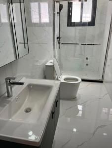 a white bathroom with a toilet and a sink at Signature Suite in Bijilo