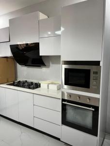 a white kitchen with a stove and a microwave at Signature Suite in Bijilo