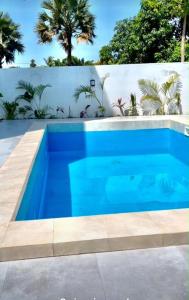 a blue swimming pool in front of a white fence at Signature Suite in Bijilo