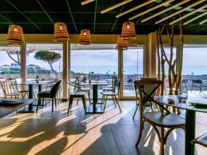 a restaurant with tables and chairs and a view of the ocean at ibis styles La Rochelle Thalasso Chatelaillon in Châtelaillon-Plage