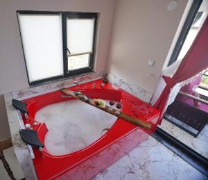 a red bath tub in a room with two windows at EYLA VİLLA in Trabzon