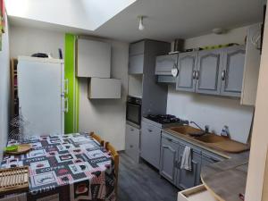 a kitchen with white cabinets and a table with a sink at Maison Relax in Flers