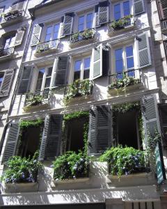 een wit gebouw met veel ramen en planten bij Hôtel des Arceaux in Bayonne