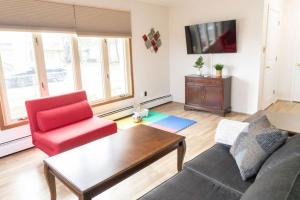 a living room with a couch and a red chair at Tranquil Retreats on Robinson in Moncton