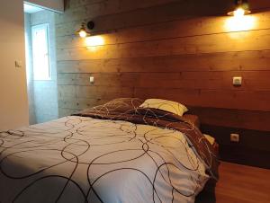 a bed in a room with a wooden wall at La cascade de Grignon - Appartement - Pizzeria - Parking Vélos - Room Service in Grignon