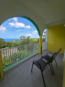 a balcony with a chair and a view of the ocean at Barefoot Apartments in Roseau