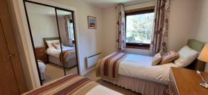 a small bedroom with two beds and a mirror at Caisteal Liath Chalets in Lochinver