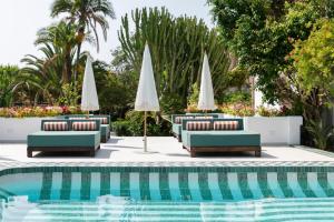 a swimming pool with lounge chairs and umbrellas at BV House - Membersclub - Adult only in Estepona