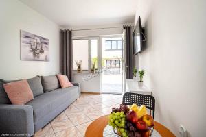 a living room with a couch and a table with a bowl of fruit at LOFT ROOMS ŁEBA in Łeba