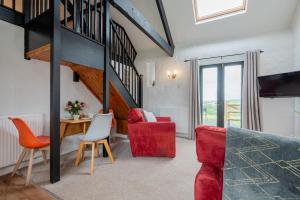 a living room with a staircase and a red chair at Trespaddick, coastal views Treworgie Barton in Bude