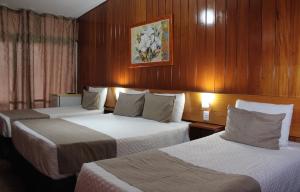 two beds in a hotel room with wooden walls at Hotel Tijuco Turismo in Diamantina