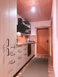 a kitchen with white cabinets and a wooden door at Ferienwohnung WAUzenberg mit Pool und Sauna in Hauzenberg