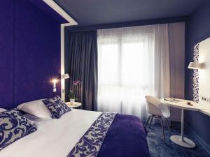 a bedroom with a bed and a table and a window at Mercure La Roche Sur Yon in La Roche-sur-Yon +75 photos