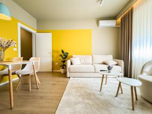 a living room with a white couch and yellow walls at All Seasons Apartments - Free Parking & City Center in Shkodër
