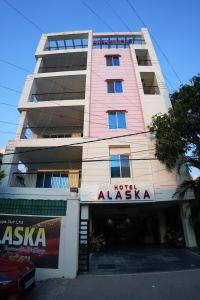 a tall pink building with a hotel alexia at Hotel Alaska in Patna