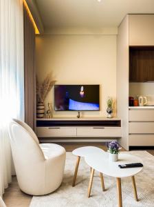 a living room with a white chair and a tv at All Seasons Apartments - Free Parking & City Center in Shkodër