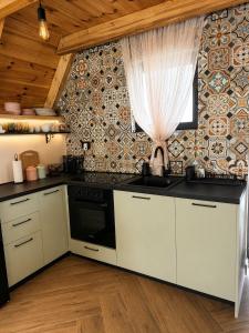 a kitchen with white cabinets and a tile wall at Monte Casa Žabljak in Žabljak