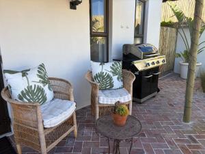 a patio with wicker chairs and a grill at Ibis Cottage Hout Bay with Mountain View Terrace in Hout Bay +14 photos