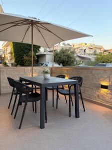 a table and chairs with an umbrella on a patio at Lumera Urban Stay - New 2BR Home with Private Parking near Old Town in Chania