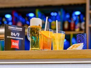 two glasses of beer sitting on a shelf with drinks at ibis Hotel Frankfurt Messe West in Frankfurt