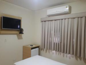 a room with a television and a window with curtains at SG Palace Hotel in Taubaté