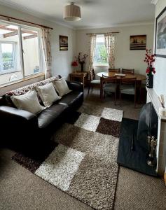 a living room with a black leather couch and a table at Airyolland in Newton Stewart