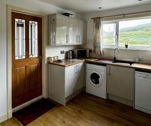 a kitchen with white cabinets and a washer and dryer at Airyolland in Newton Stewart