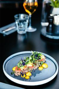 a plate of food on a table with a glass of wine at Radisson Blu Royal Garden Hotel, Trondheim in Trondheim