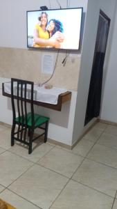 a tv on a wall with a table and a chair at Suites in Domingos Martins