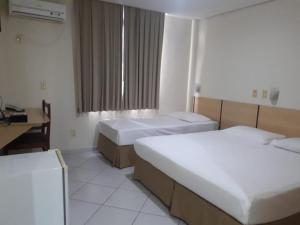 a hotel room with two beds and a desk at SG Palace Hotel in Taubaté