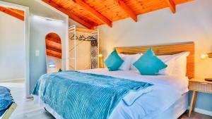 a bedroom with a large bed with blue pillows at The Fisherman's LAB Cabin in Hermanus