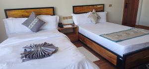 two beds in a room with white sheets at Cornerstone Hotel Arusha in Arusha