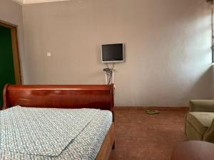 a bedroom with a bed and a tv on the wall at ODeTTe GUEST HOUSE in Kumasi