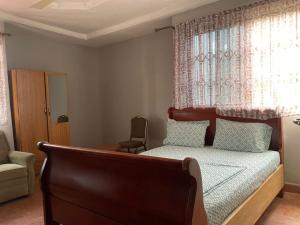 a bedroom with a bed with a chair and a window at ODeTTe GUEST HOUSE in Kumasi